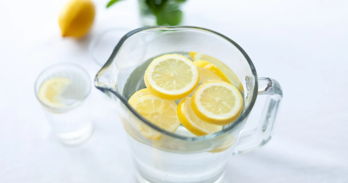 Glass pitcher filled with lemon slices and water.
